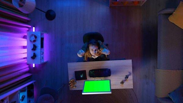 Gaming and streaming advertisement concept. Person on the PC at home. Top view of male at the monitor with Chroma key green screen, won the mission in the game, advertising area workspace mockup.