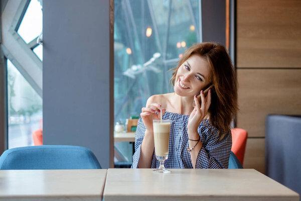 Cheerful young lady at the restaurant talking on the phone