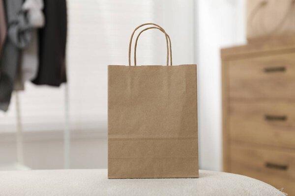 Paper bag on white pouf indoors, closeup