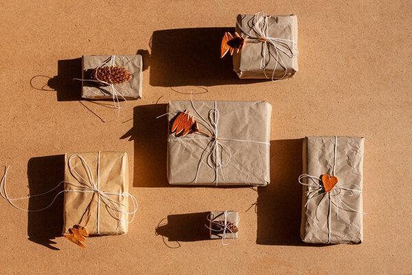 Zero waste Christmas concept flat lay with hard shadows. Hand crafted eco gifts with natural New Year jute decorations top view. Kraft paper wrapping without plastic. Orange zest trees, hearts, cones.