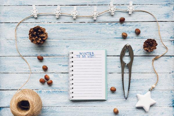 Notepad with Winter To Do List text on a blue and white wooden background. Top view, flat lay, mockup. Winter, Christmas and New Year celebration and resolutions concept.
