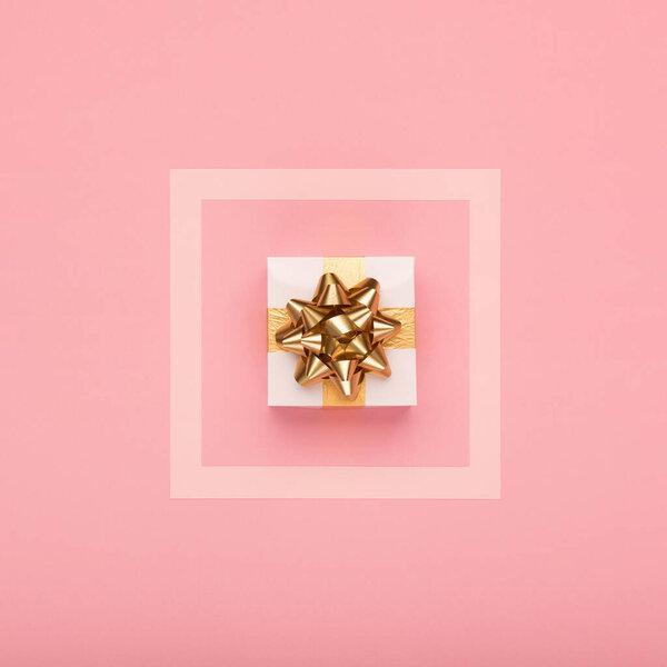 Festive holiday greeting card template. Golden tropical leaves Monstera, festive gift box and gold decorations on amaranth pink background. Christmas, new year concept. Flat lay, top view, copy space.