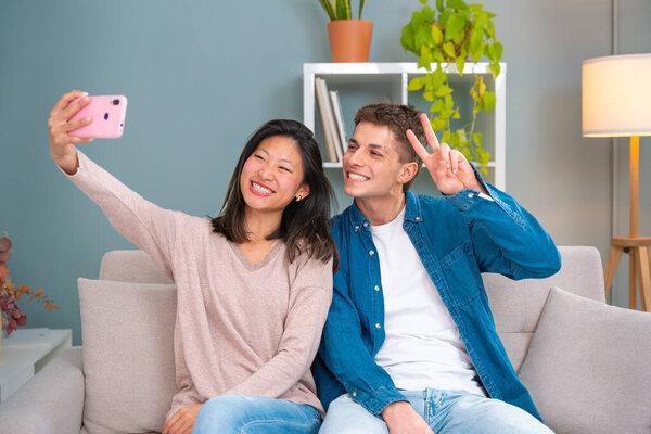 Young smiling multiracial friends taking a selfie in living room. Concepts of youth, peoples lifestyle, diversity, urban life