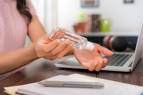 Woman working, home office laptop applying Hand sanitizer Small portable squeezable dispenser alcohol gel coronavirus quarantine
