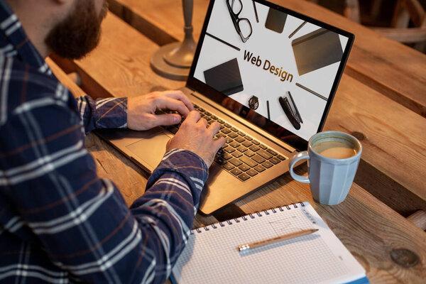 Cropped image of a young man working on his laptop in a coffee shop, rear view of business man hands busy using laptop at office desk, young male student texting on computer sitting at wooden table