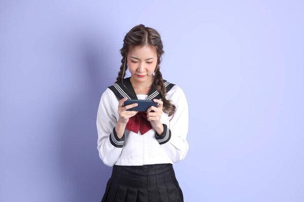 身穿日本校服的亚洲女孩站在紫色的背景上.