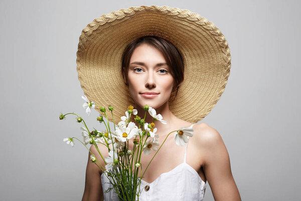 戴着花帽子的快乐的女孩。美丽而快乐的年轻女子，戴着菊花
