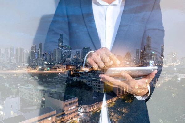 Businessman using tablet. Double exposure image of business man and city night view.
