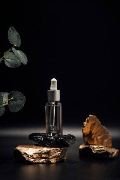 Essential oil for facial skin care, a glass bottle with a pipette on a stone