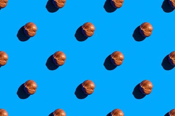 Hazelnuts background. A trendy sunlight pattern made of hazelnuts against a bright blue background. Colorful pattern. Top view