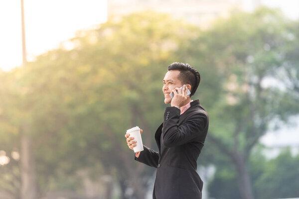 Young Malay Business Man on his Smartphone with a cup of coffee.