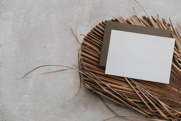 Mockup tropical invitation, blank greeting card with dry tropical palm leaves. Flat lay, top view.
