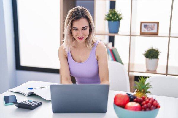 Young woman sitting on table teleworking at home