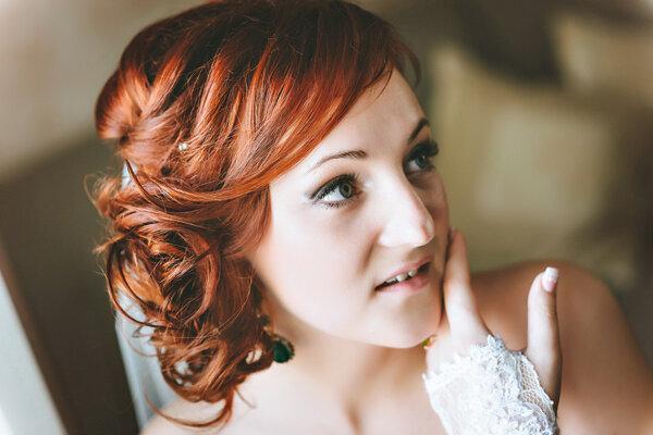 portrait of red-haired young bride, smiling, hand near the face