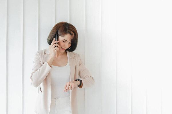 Happy Asian working woman is having a smartphone conversation.