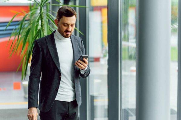 Young smiling businessman calling on phone at office.