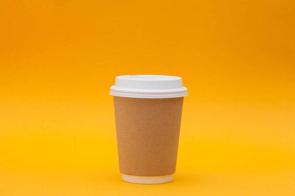 Paper coffee container with white lid on orange background. Takeaway drink cap container. Template of drink cup for your design. Free space for input text, image, and logo. Colored background.