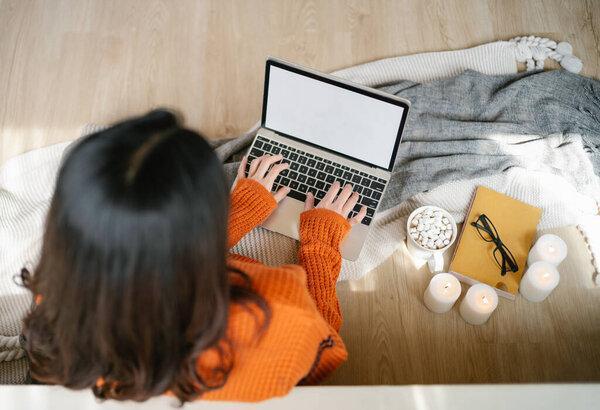 Top view of woman freelancer wearing sweater sitting on floor using laptop blank screen white background at home. Technology And Gadgets, Freelance Career And Lifestyle Concept. Top View Shot, Mockup