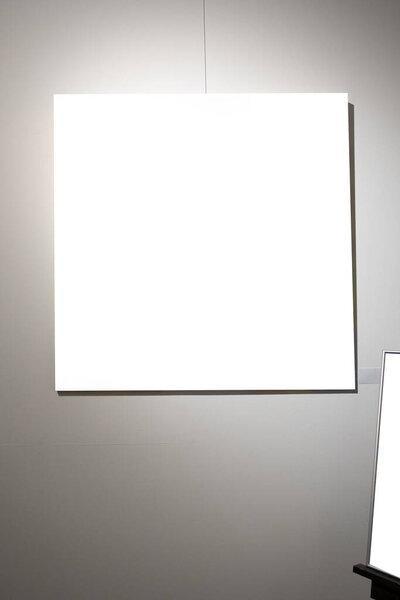 Blank picture frames on grey wall with glowing lamp in the gallery , mock up