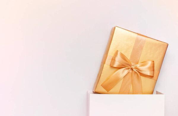 Beautiful golden gift white paper bag on gray background top view Flat lay. New Year presents Festive decorations celebration. Merry Christmas Surprise congratulation birthday March 8 mothers Day.