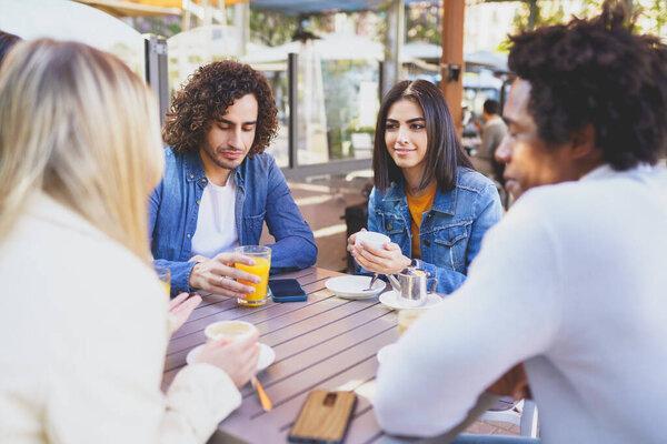 Multi-ethnic group of students having a drink on the terrace of a street bar.