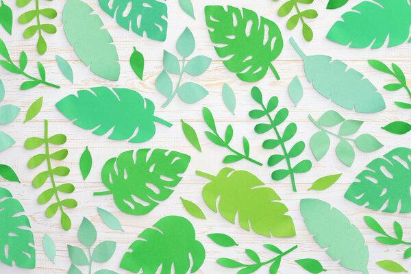 Composition of cut paper tropical palm leaves, Monstera and banana leaves. Handmade nature mockup, summer art collection isolated on white wooden background. Top view, flat lay, full cover, close up