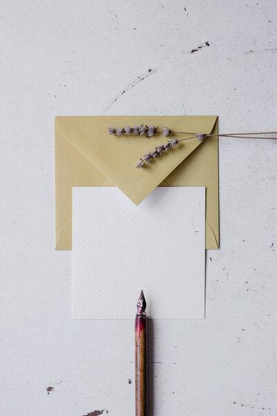 Simple wedding card mockup with lavender flowers, craft envelope and pencil. Top view. Copy space