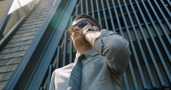 Businessman with mobile phone outside of the office. Steel lines from office building behind him