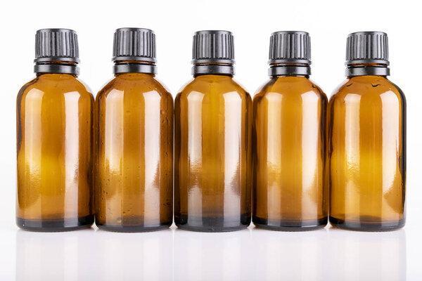 Small glass bottles for the storage of light-sensitive liquids. Containers used in pharmaceuticals. Light background.