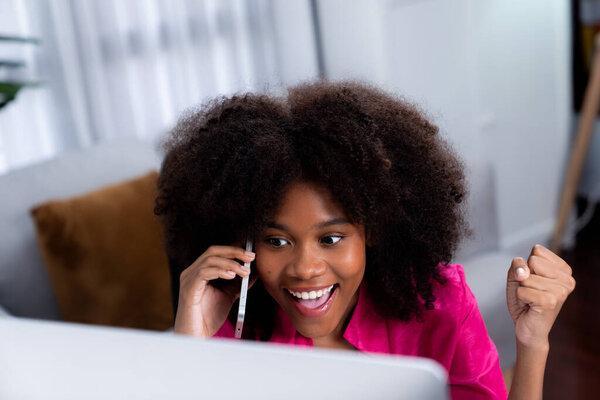African woman talking with coworker or friend on the phone and looking at the screen with happy face. Achievement for promoting job position in the company with the good news life. Tastemaker.