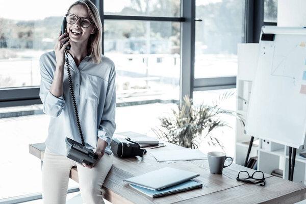 Joyful cute woman sitting and having phone conversation.