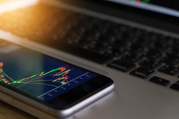 Businessman analyse stock market using mobile smart phone and la