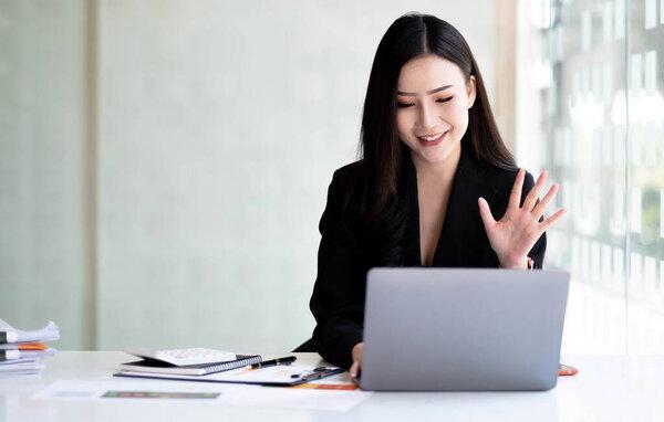 Shot of Asian young business woman looking and speaking through the webcam while making a video conference from the office