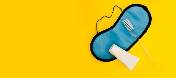 Tooth brush. Toothpaste. Mask for sleep. Getting ready for bed. Minimalistic yellow background.