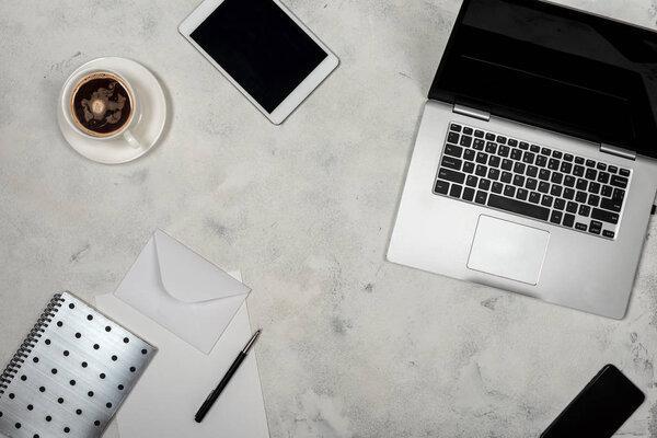 Workspace with laptop, tablet, smartphone, notebook and a cup of coffee. Top view of freelancer working place.