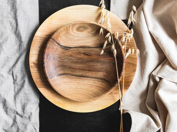Round wooden craft plates mockup for eco, food or beauty product on black and textile backgrounds. Top view. Copy space