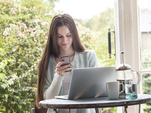 Young woman sitting at table, looking at smartphone