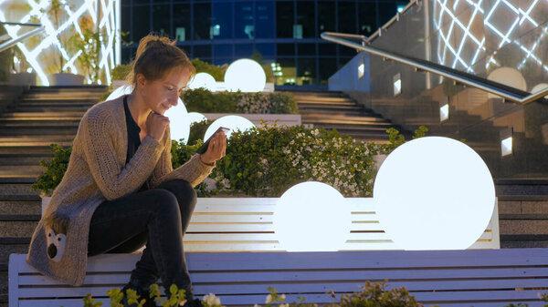 Woman using smartphone in the city at night