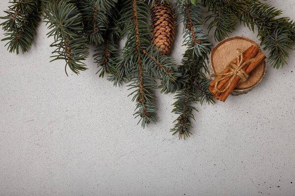 Blue fir tree branch with cone, wooden cut and cinnamon sticks on white wooden background. Christmas card, copy space