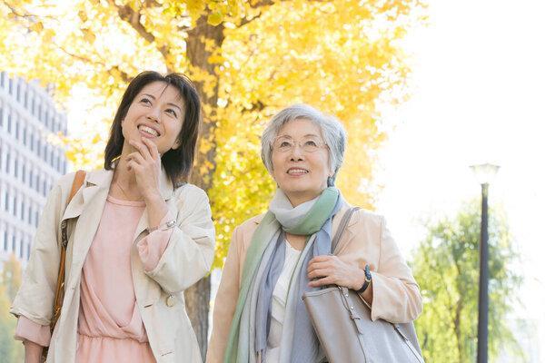 快乐的年长而成熟的日本女人在秋天的公园里散步