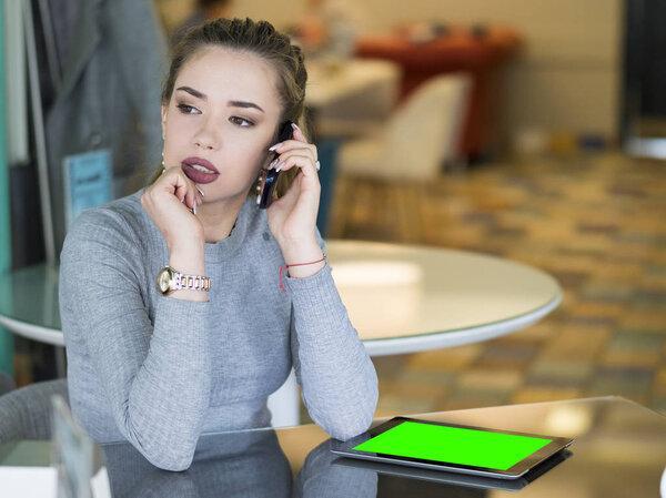 Pensive. Annoyed thoughtful woman funny student with pad looking down at digital tablet thinking perplexed puzzled standing near a clothing store outdoors of her office background. Mock up