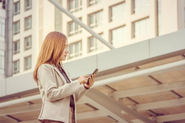 Close up Portrait of young beautiful casual businesswoman using smartphone in the city backgroun