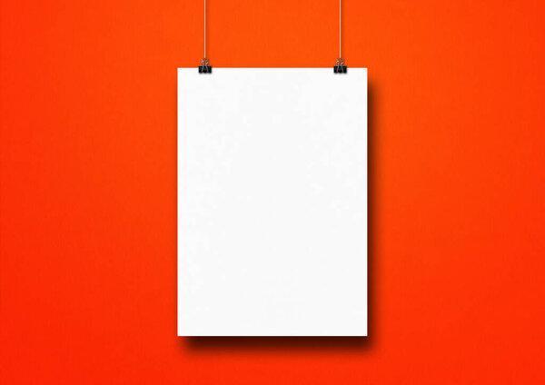 White poster hanging on a red wall with clips. Blank mockup template