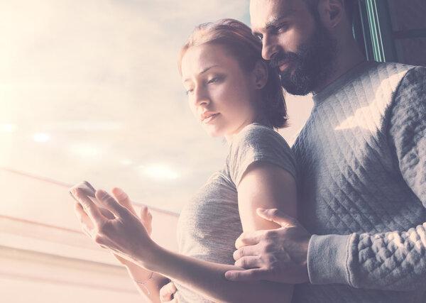Adult couple romantic journey. Photo woman and bearded man using mobile phone. Girl touching screen contemporary smartphone. Horizontal, film effect.