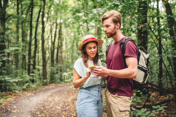 Hikers using mobile gps for directions. Happy couple checking smartphone in the woods during backpacking trip. Young joyful couple using gps map, navigator geolocation app. love and travel concept.