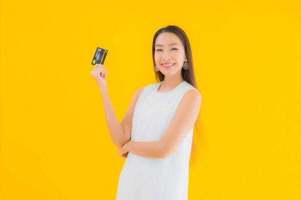 亚洲年轻貌美的女性形象- -带着信用卡在黄色隔离背景下网上购物