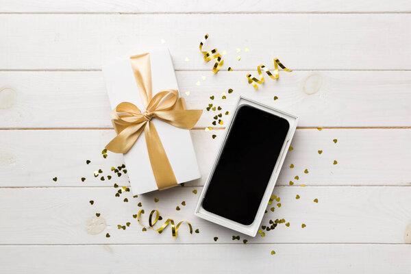 Opened gift box with gold ribbon and smartphone on color background, top view. Blank open box packaging mockup , Template for your design - branding mockup.