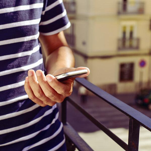 young man using his smartphone in the balcony
