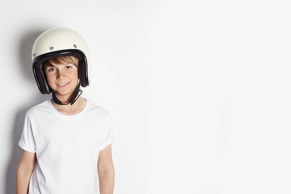 Happy young cute cheerful teen boy in white tshirt draming to ride a motorcycle isolated on white background.