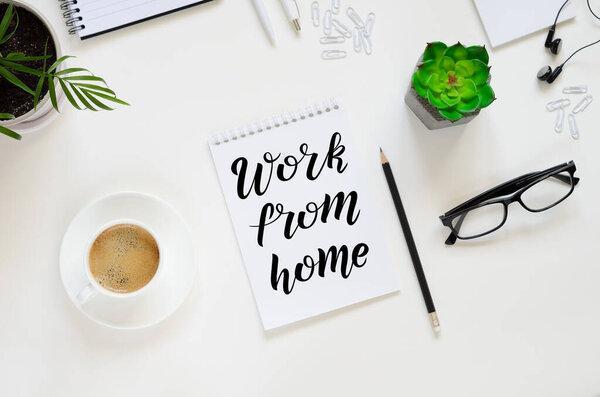 Workspace with pen, paper, coffee cup, glasses and office supplies. Top view flat lay overhead. Work From Home lettering